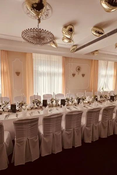 Barockzimmer im Goldenen Pflug in Ludwigsburg mit großer Hochzeitstafel, weißen Stuhlhussen, Blumendekoration und goldenen Herzballons.