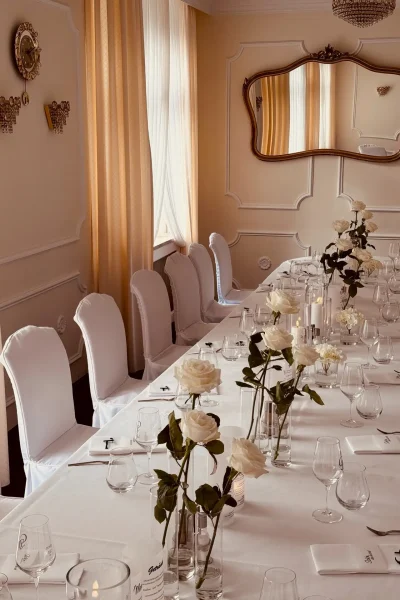 Festlich gedeckte Tafel mit weißen Rosen, Kerzen und weißen Stuhlhussen im Barockzimmer des Goldenen Pflugs in Ludwigsburg.