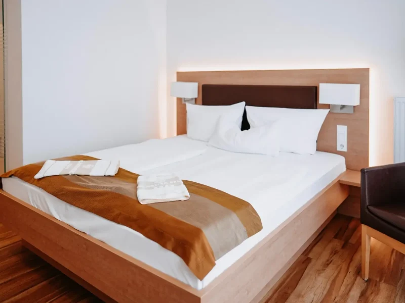Gesamtansicht eines Doppelzimmers mit kleinem Doppelbett und Sessel im Hotel Goldener Pflug Ludwigsburg