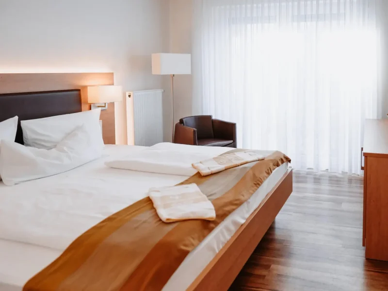 Doppelzimmer mit kleinem Doppelbett, Sessel und hellem Fensterbereich im Hotel Goldener Pflug Ludwigsburg