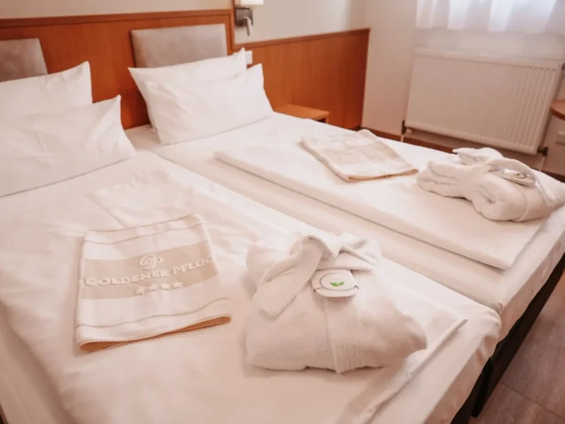Doppelzimmer Standard mit zwei Betten, Bademänteln und Handtüchern im Hotel Goldener Pflug Ludwigsburg