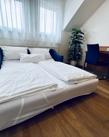 Hotelzimmer mit Doppelbett, Schreibtisch und Fernseher.