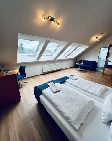 Helles Dachgeschosszimmer mit zwei Betten und Schreibtisch.
