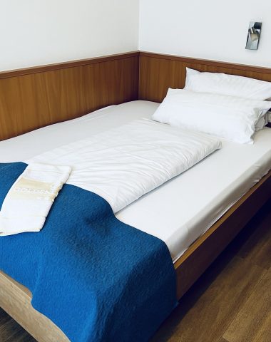 Hotel room with neatly made single bed.