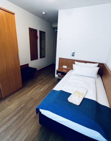 Einzelzimmer mit Bett und Schrank in Hotelzimmer.