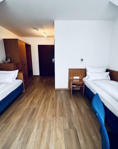 Zweibettzimmer mit Holzboden und Einrichtung.