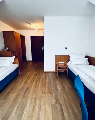 Zweibettzimmer mit Holzboden und Einrichtung.