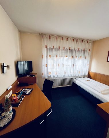 Gemütliches Einzelzimmer mit Schreibtisch und Fernseher.