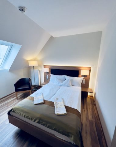 Gemütliches Dachgeschoss-Schlafzimmer mit Holzboden und Doppelbett.