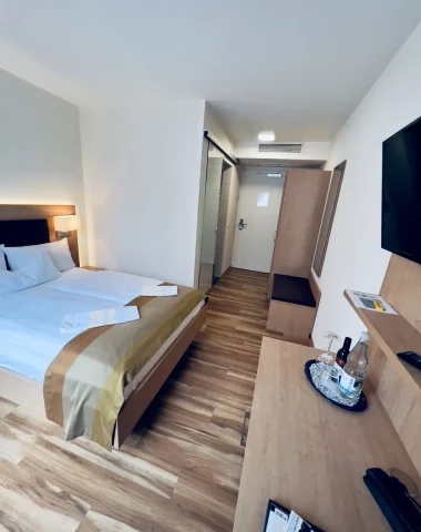 Modernes Hotelzimmer mit Doppelbett und Fernseher.