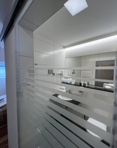 Modernes Badezimmer mit Spiegeln und weißer Einrichtung.