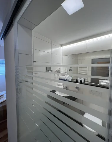 Modernes Badezimmer mit Spiegeln und weißer Einrichtung.