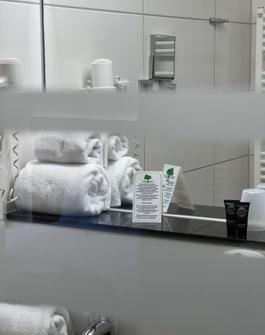 Moderne Hotelbadezimmerausstattung mit Handtüchern und Pflegeprodukten.