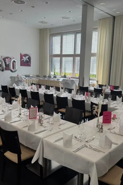 Festlich eingedeckter Saal im Goldenen Pflug Ludwigsburg mit Tafeln in E-Form und dunklen Stühlen.