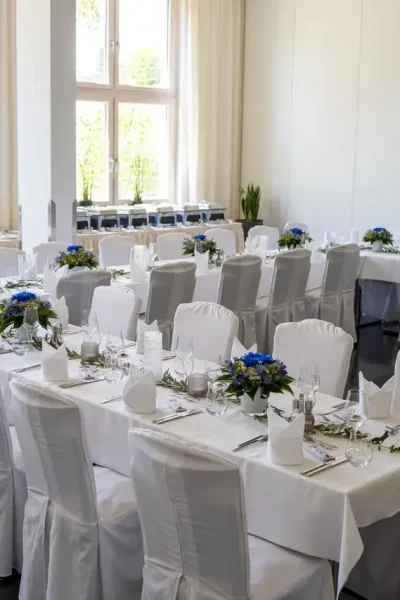 Festlich dekorierter Saal im Goldenen Pflug Ludwigsburg mit weißen Stuhlhussen, Blumenschmuck und mehreren Tafeln für eine Hochzeitsfeier.