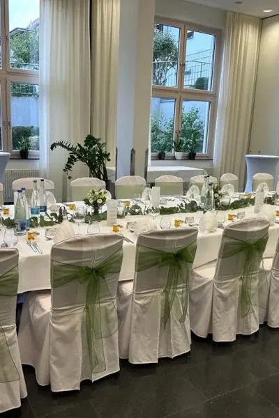 Lange festlich gedeckte Tafel mit weißen Stuhlhussen und grünen Schleifen im Saal des Goldenen Pflugs in Ludwigsburg.