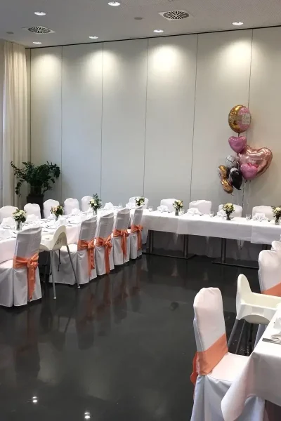 U-förmig gestellte Festtafel mit weißen Stuhlhussen und floraler Dekoration im Saal des Goldenen Pflugs in Ludwigsburg.