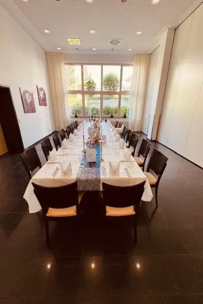 Salon 2 im Goldenen Pflug Ludwigsburg mit langer gedeckter Tafel und großer Fensterfront.