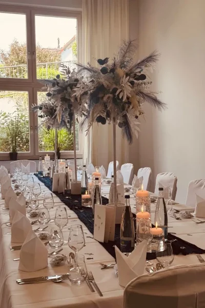 Festlich gedeckte Tafel mit floraler Dekoration und Kerzen in Salon 3 des Goldenen Pflugs in Ludwigsburg.