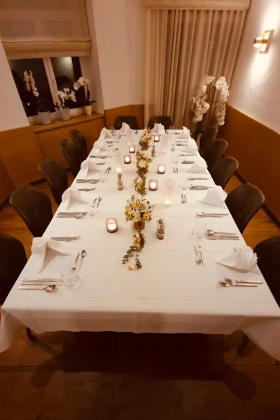 Abendlich gedeckte Festtafel mit Kerzen und Blumendekoration im Raum Tisch 19 des Goldenen Pflugs in Ludwigsburg.