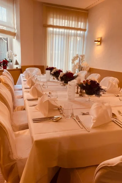 Festlich gedeckte Tafel mit weißen Stuhlhussen und Blumendekoration im Raum Tisch 19 des Goldenen Pflugs in Ludwigsburg.