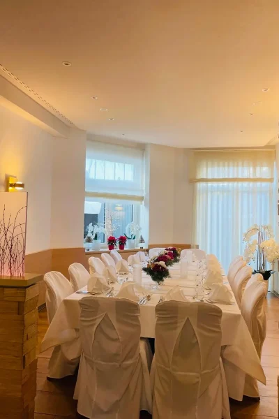 Raumansicht von Tisch 19 im Goldenen Pflug Ludwigsburg mit langer gedeckter Tafel und weißen Stuhlhussen.