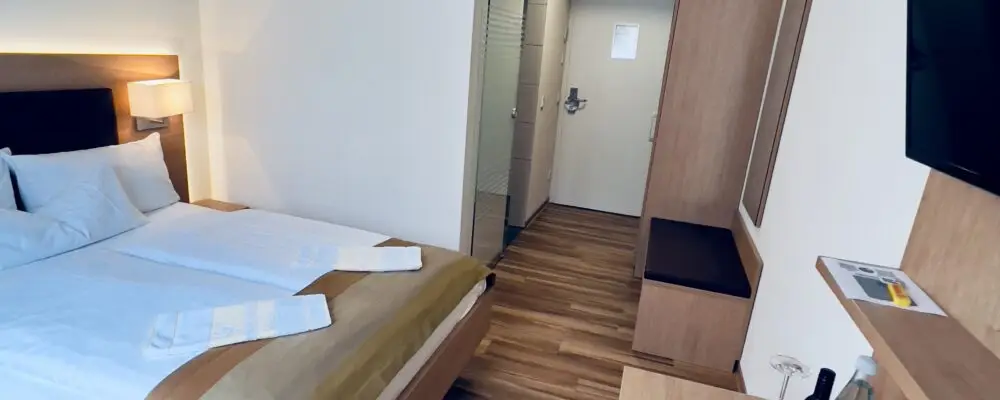 Modernes Hotelzimmer mit Doppelbett und Fernseher.