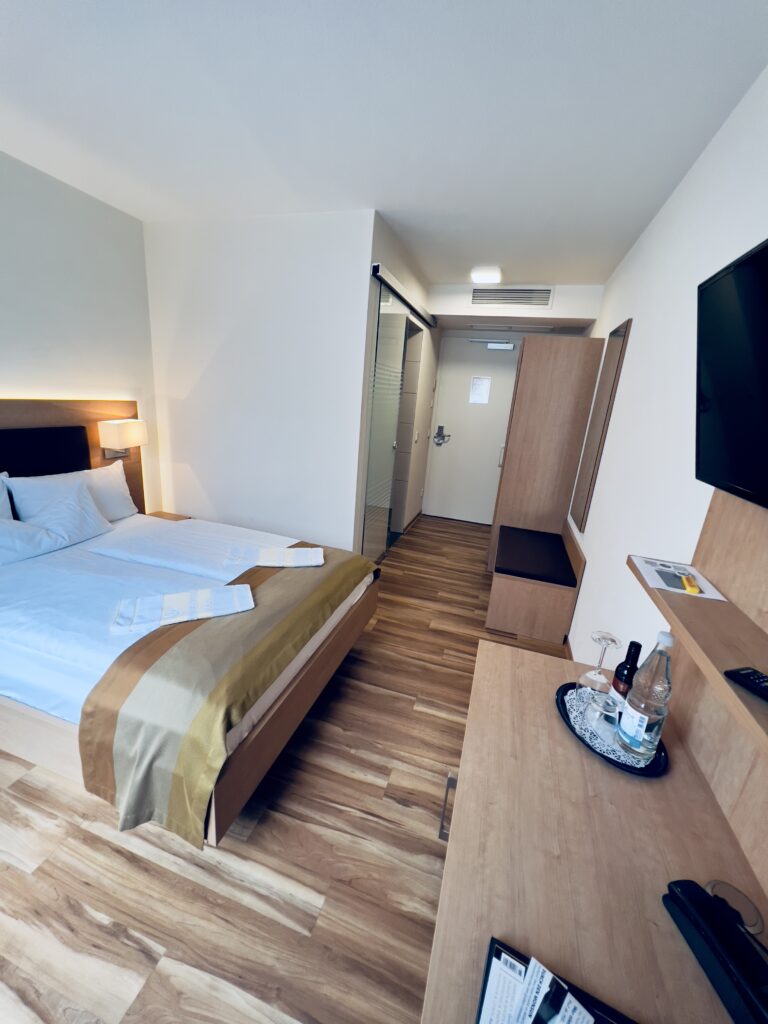 Modernes Hotelzimmer mit Doppelbett und Fernseher.