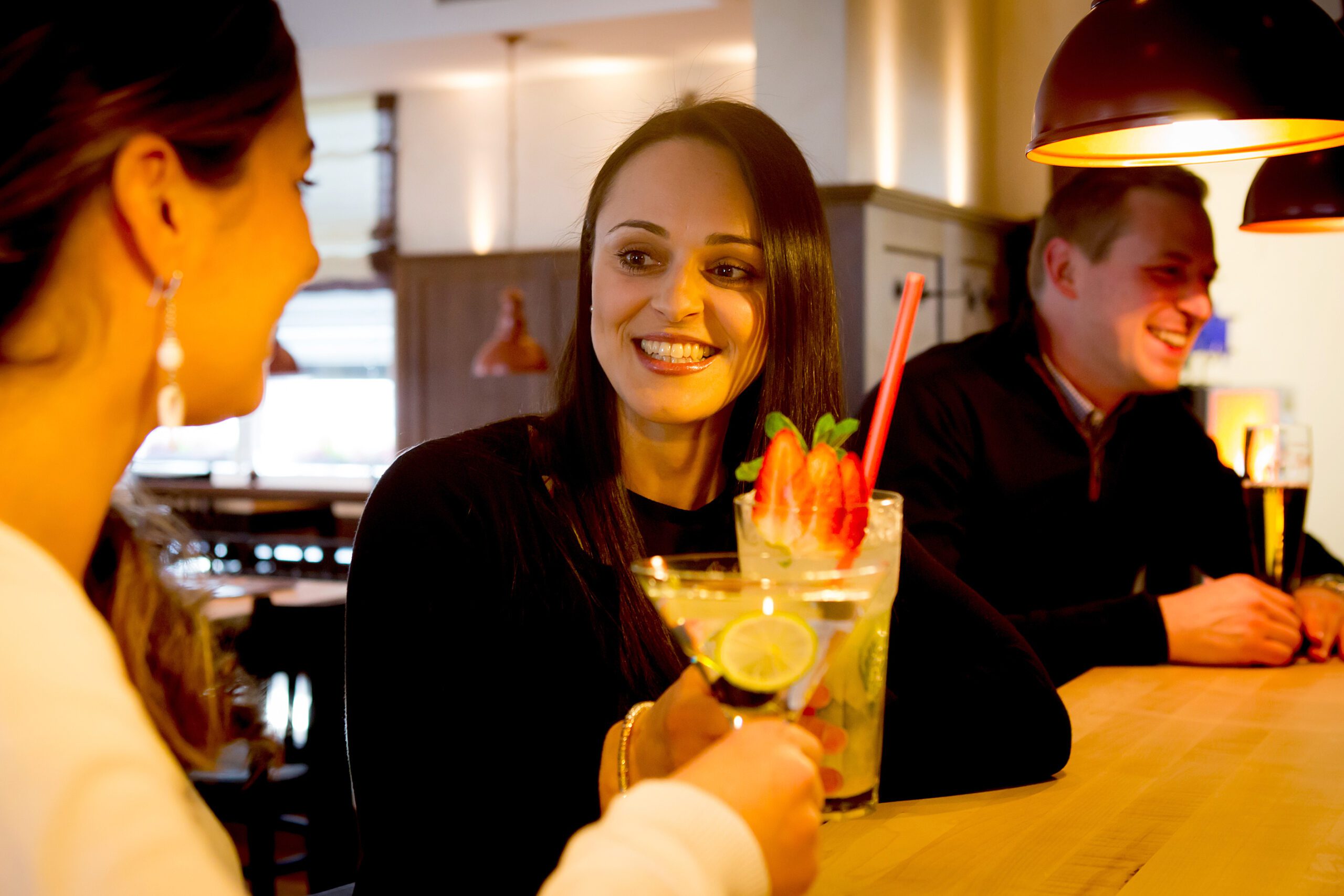 Frau genießt Cocktail mit Freunden in Bar.