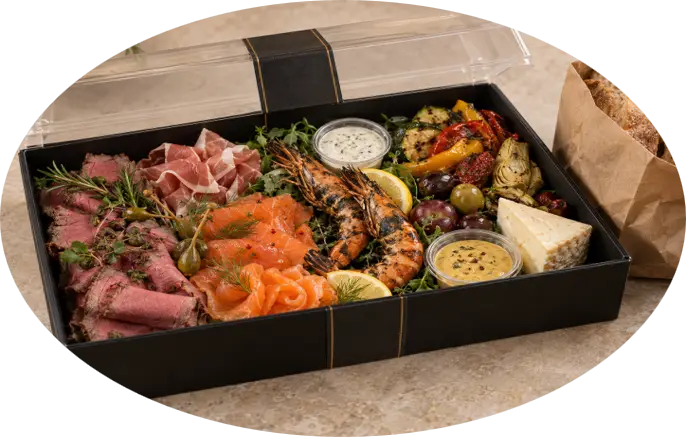 Silvesterplatte mit Roastbeef, Schinken, Lachs, Garnelen, Käse, Antipasti und Dips in einer schwarzen Cateringbox.